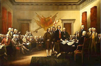 About 50 men, most of them seated, are in a large meeting room. Most are focused on the five men standing in the center of the room. The tallest of the five is laying a document on a table.